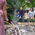 Beim Stockbrot backen | © FZM Bild: Eltern und Kinder beim Stockbrotbacken um ein Lagerfeuer herum.