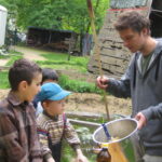 So wird der Teig gemacht | © FZM Bild: Jugendlicher Erzieher zeigt Kindern die Herstellung des Teiges für das Stockbrot