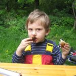 Moabiter KinderHof - Lecker! Stockbrot mit Nusscreme Bild Kind isst Stockbrot mit Nusscreme an einem Tisch