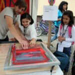 PerlenKiezfest 2012 Bild: Siebdruckerei - ein Mädchen und der Drucker stellen einen Siebdruck her