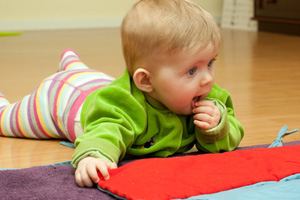 Bild Baby spielt bauchliegend auf dem Fußboden