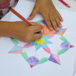 Bild - Hände auf einem Tisch beim ausmalen auf Papier