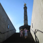 Bild - Blick auf die Siegessäule von unten aus der Unterführung, zwei Mädchen auf der Treppe der Unterführung davor