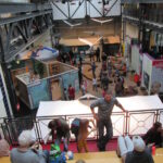 Bild: Blick von einem oberen Rang, auf dem Kinder und Eltern sitzen, in die Halle des Museums