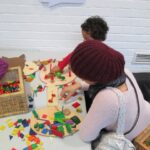 Bild: zwei Kinder spielen mit buntem Holzfiguren auf eunem Tisch