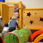 Bild: Kleinkinder klettern mit Hilf einer Mutter in eine Kletterburg