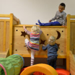 Bild: auf der Kletterburg. Zwei Kinder klettern nach oben und eines schaut von oben herunter.