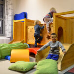 Bild: auf der Kletterburg. Zwei Kinder kletter nach oben und eines Rutsch die Rutsche herunter.