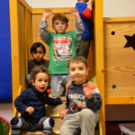 Bild: auf der Kletterburg. Mehrere Kinder winken.