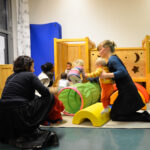 Bild: Junge Mütter spielen mit ihren Kleinkindern auf einer Krabbelburg