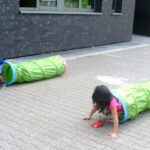 Bild: Mädchen kriecht aus einem Krabbelschlauch