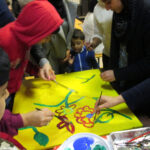 Auch die Mütter sind kreativ und malen tolle Bilder. | © FZM Bild: Kinder bemalen eine gelbe Leinwand mit bunten Blumen
