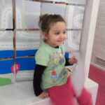 Bild: Kins sitzt auf der Kante eines Ausstellersockels.