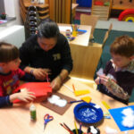 Bild: Mutter mit zwei Kindern bastelnd an einem Tisch