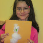 Bild: Mädchen hält ein Bild mit einem Schneemann aus Watte