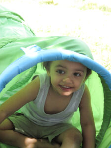 Bild: Kind guckt aus einem Spieltunnel heraus