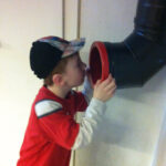 Bild: Junge ruft in eine Regenabwasserroh an der Wand