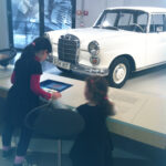 Bild: zwei Kinder vor einem Ausstellungsstück Auto