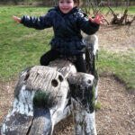 Ausflug zur Domäne Dahlem | © FZM Bild: Junge sitzt freihändig auf einem großen Holzhund