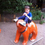 Bild: Kind sitzt essend auf einem Berliner Bär Skulptur