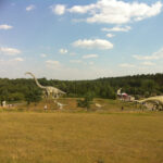 Bild: Mehrere unterschidlich große Dinosaurier-Nachbildungen auf eine hügeligen Landschaft