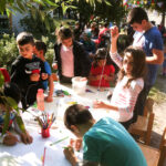 Bild: 7 Kinder basteln und malen an einem Tisch im Freien