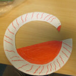 Bild: Ein aus einem Pappteller gebastelter Schwan auf einer Holztischplatte