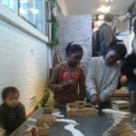 Wir bauen unsere eigene Stadt | © FZM Bild: Kinder bauen auf einem Tisch Häuser aus kleinen Holzbauklötzen