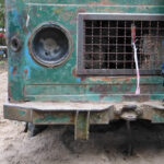 Klettern war heute erlaubt! | © FZM Foto: untere Front eines sehr alten grünen LKW. Linksseitig Bein eines auf der Stoßstange stehenden Kindes.