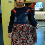 Prinzessinnen gab es auch | Foto: © FZM Foto: Mädchen mit weiß-rot-schwarz gemustertem Rock, bunt bemaltem Gesicht und Krone auf dem Kopf mit Blick zum Betrachter vor einer Wand mit Spiegel.