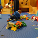 Auch die ganz Kleinen feierten mit | Foto: © FZM Foto: 3 Kleinkinder spielen mit diversem Spielzeug auf dem Fußboden. Rückenansicht.