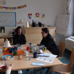 Frau Dr. Obermeyer stellt sich vor | © FZM Foto: Frau sitzt rechts an einem Tisch, rechts von ihr sitzt ein junger Mann. Besprechnungssituation. Flipchart im Hintergrund.