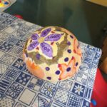 Foto: eine bunt bemalte Styropor-Halbkugeln auf einem Tisch mit blau gemusterter Tischdecke