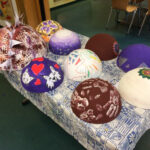 Foto: 9 bunt bemalte Styropor-Halbkugeln auf einem Tisch mit blau gemusterter Tischdecke