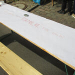 Foto: Tisch diagonal über das Bild mit zusammengeklebten weißen Papierblättern und Schriftzug: Was bedeutet Familie für Dich.