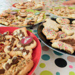 Foto: Plätzchen mit Zuckerguß und bunten Streuseln auf Tellern auf einer bunt bepunkteten Tischdecke