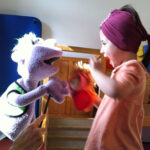 Foto: Kind spielt mit einer auf einem Arm gehaltenen Stofffigur