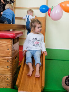 Foto: Mädchen rutscht lachend auf einer Holzrutsche