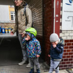 Foto: 2 Kinder stehen mit ihrem Vater wartend in einer Tordurchfahrt