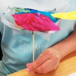 Foto: Kinderhand hält einen aus Klopapierrollen, bunten, gebastelten Vogel