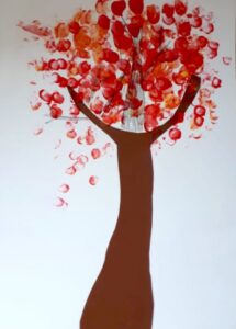 Foto: Ein mit Pappe und rot-orangenen Fingerfarben aufgemalter und -geklebter Baum