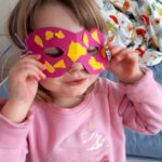 Elisa, 4Jahre | Foto: © FZM Foto: Kind mit rose Pullover hält sich eine selbstgebastelte rosa-gelbe Maske vors Gesicht