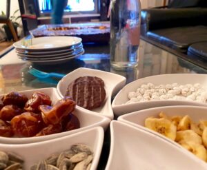 Foto: kleine Schälchen mit Datteln, Kernen, Keksen und Bananenchips, im Hintergrund ein Fernsehr