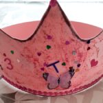 Selma, 4 Jahre | Foto: © FZM Foto: rosa selbstgebastelte Krone mit Glitzer und einem Schmetterling