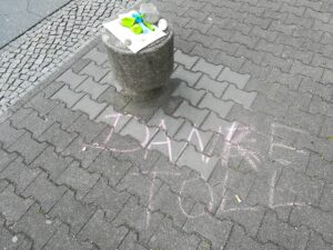 Foto: Poller auf der Straße, mit Ballons und Pustefix drauf, davor geschrieben mit Kreide "Danke Toll"