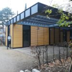 Foto: Ein gelber Pavillion frontal mit großer Glasfront rechts