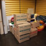 Foto: Umzugskisten und verpacktes Spielzeug vor einer gelben Wand