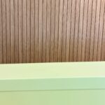 Fotot: Holzwand hinter hellgrünem Gerüst