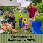 Ein Bild vom Camping. Darauf zu sehen sind Väter mit ihren Kindern (zensiert), einem Hund und aufgebaute Zelte.