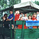 Domäne Dahlem Express Bild: Mehrere Kinder winken von einem grünen Traktoranhänger